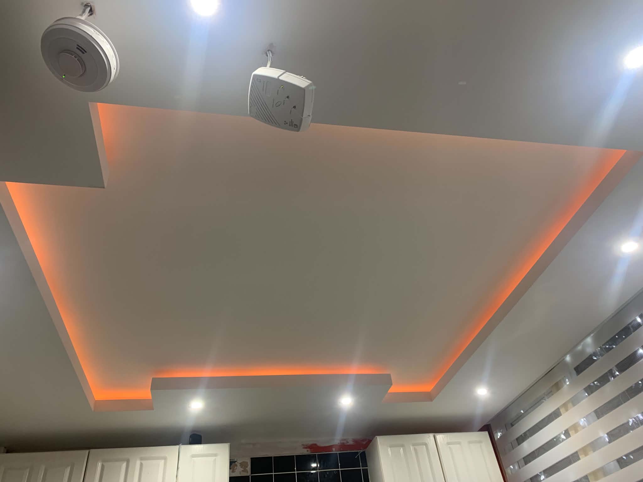 Bespoke ceiling with recessed bulkhead and colour-changing LED lighting above a media wall